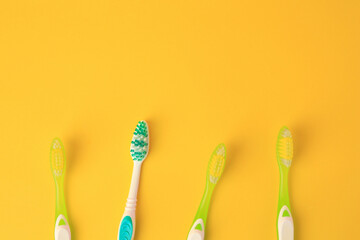 New toothbrushes on yellow background, flat lay. Space for text