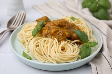 Delicious pasta and chicken with curry sauce served on white tiled table, closeup