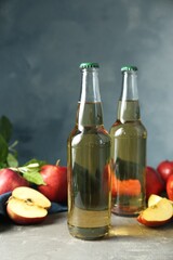 Delicious cider and apples with green leaves on gray table, closeup