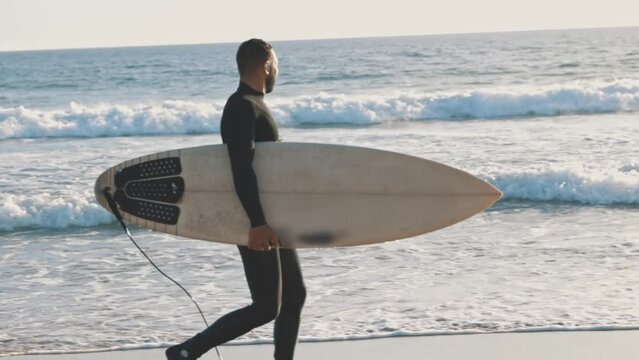 Surfer walking on the beach with a large surfboard
