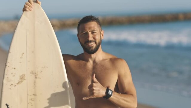 urfer holds his board and shows shaka gesture