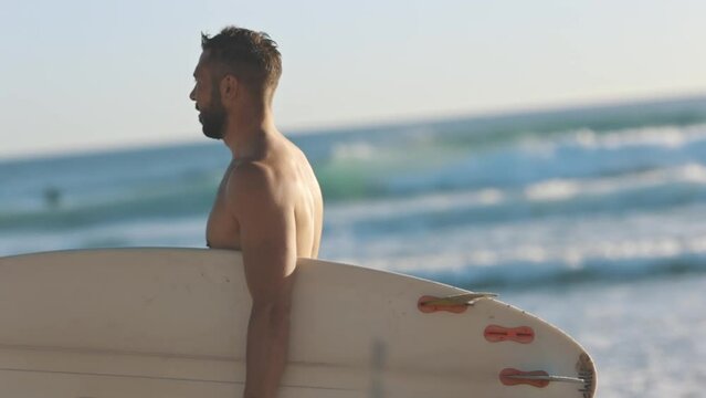 Sportsman surfer walk along coast with surfboard