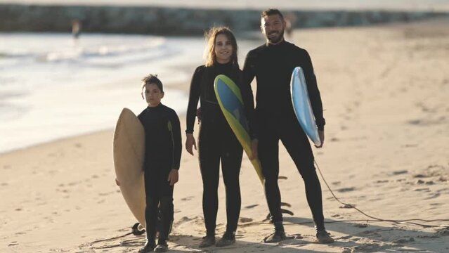 Family of surfers on beach with surfboards 