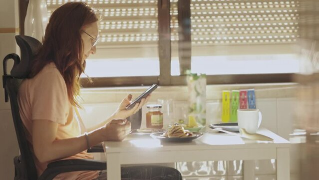 Young woman looking her phone during the breakfast