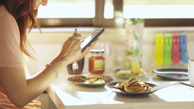Woman eat pancake for breakfast and looks at phone