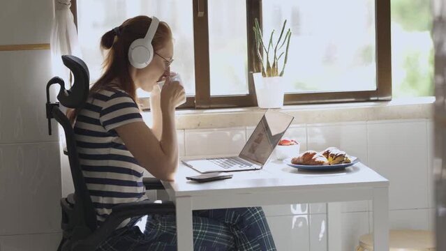 Young woman with laptop drink coffee for breakfast