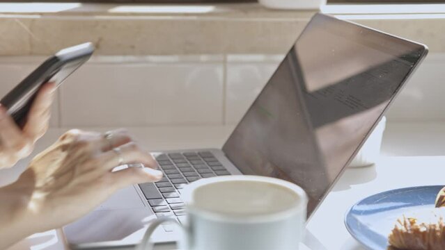 Close-up of female hands with phone and laptop