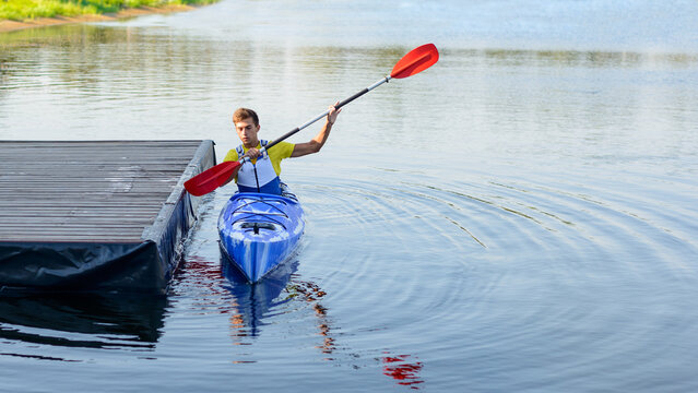 Young Professional Kayaker Paddling Kayak on the River under Bright Morning Sun. Sport and Active Lifestyle Concept