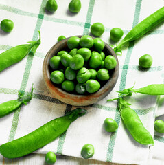 Fresh Green Pea in Wooden Bowl with Pods closeup on Checkered Napkin