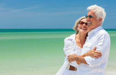 Happy laughing senior man and woman retired couple embracing wearing sunglasses on a deserted...