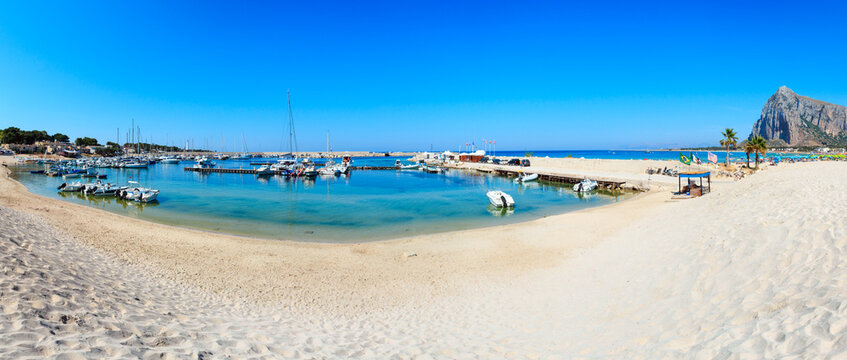Tyrrhenian sea bay and port with boats, San Vito lo Capo beach with clear azure water and extremal white sand, Sicily, Italy. People are unrecognizable. Two shots stitch high-resolution panorama