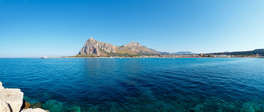 San Vito lo Capo beach with clear azure water and Monte Monaco in far, north-western Sicily, Italy. People are unrecognizable. Two shots stitch panorama.