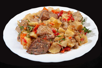 Plate with roasted meat and potatoes on a black studio background