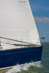 Obraz premium Close up of sailing boat, sail boat or yacht with a blue hull and white sails at sea