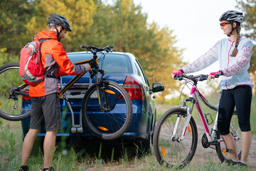 Young Couple Preparing for Riding the Mountain Bikes in the Forest. Unmounting the Bike from Bike...