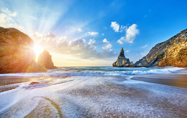 Portugal Ursa Beach at atlantic coast of Atlantic Ocean with rocks and sunset sun waves and foam at sand of coastline picturesque landscape panorama.