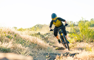 Professional Cyclist Riding the Downhill Mountain Bike on the Summer Rocky Trail at the Evening....