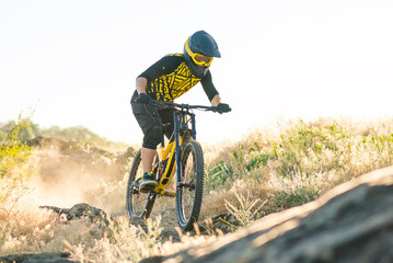 Professional Cyclist Riding the Downhill Mountain Bike on the Summer Rocky Trail at the Evening....