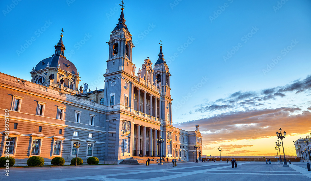 Wall mural Madrid, Spain. Cathedral Santa Maria la Real de la Almudena at Plaza de la Armeria. Famous landmark with sunset sunand. Street lamps and picturesque sky with clouds.