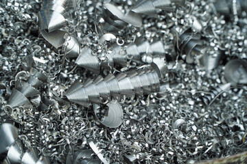 Steel scrap materials recycling. Aluminum chip waste after machining metal parts on a cnc lathe. Closeup twisted spiral steel shavings. Small roughness sharpness,