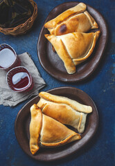 Tipical Chilean baked empanadas de pino y napolitano on clay plates with wine. Dish and drink on 18...