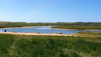 Blue sky, green grass, and river.