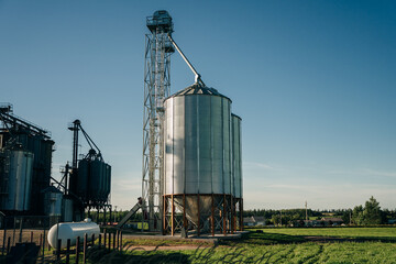 Fototapeta na wymiar Modern Granary elevator. Silver silos on agro-processing and manufacturing plant for processing drying cleaning and storage of agricultural products, flour, cereals and grain.