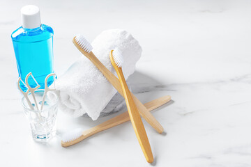 Bamboo toothbrush on towel with mouthwash and floss on white table