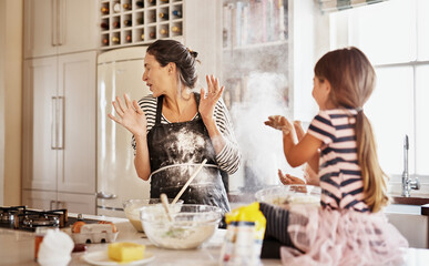 Mother, playing or girl baking in kitchen as a happy family with a playful young kid with flour at home. Dirty, messy or funny mom helping, cooking or teaching daughter to bake for child development