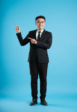 full body image of young businessman posing on blue background