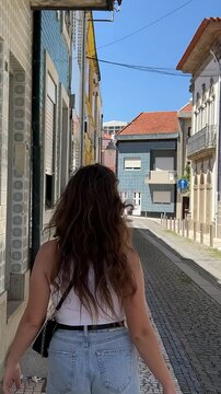 a girl in dark glasses in a white T-shirt and jeans walks along a stone street Povoa de Varzim city in Portugal and its streets and nature High quality 4k footage