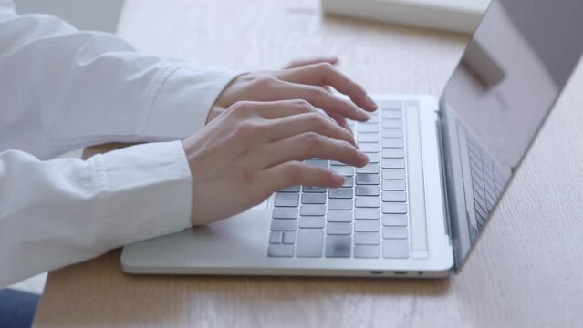 リビングにてノートパソコンを使用してリモートワークを行う30代の日本人女性