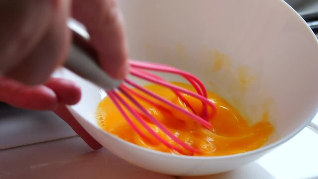 A woman's hand whips an egg with a special silicone whisk. Making slow motion homemade buns