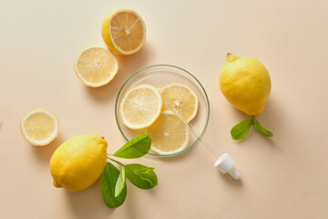 Promotional scene for cosmetics and skin care products with natural vitamin c - fresh lemon, lime slices and green leaves decoration on a beige background.