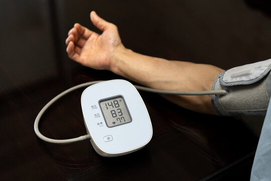 Middle-aged man is taking a self-test of his blood pressure with an electronic blood pressure monitor. The device gives a reading of hypertension. 