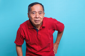 Senior man  wearing red t-shirt with serious expression on face looking at the camera. 