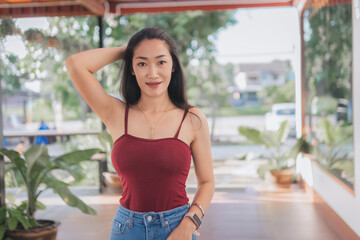 Portrait of asian beautiful sexy asian woman sitting smiling and relaxing Wearing a red strapless dress and jean skirt in a coffee shop