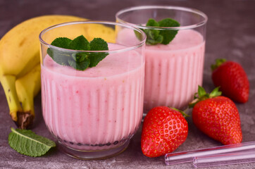 Two strawberry-banana smoothies on a gray background.Close-up.	