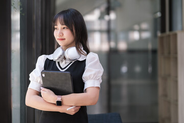 Smiling young woman college student holding digital tablet and  looking away. Education, learning, and knoeledge.