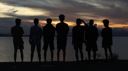 Fototapeta na wymiar Silhouette of a group of people by the lake with a beautiful sunset