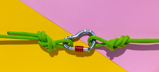 carabiner with a rope lies on a colored background. Equipment for climbing and mountaineering. reliable connection. Safety rope. Node eight. the concept of reliability and strength.