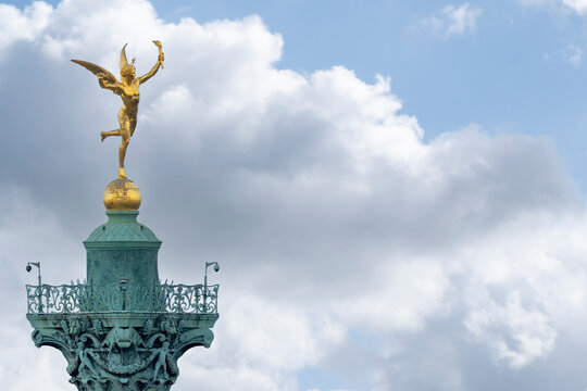 Close up detail of gilded winged Mercury atop the Bastille Column in Paris France with copy space on a blue sky cloud background