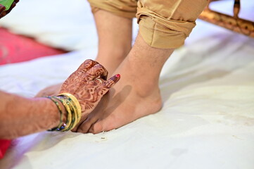 feet of a Indian Groom. Hands of mother drawing symbol on groom legs. Marathi Wedding Rituals....