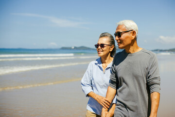 Romantic Senior couple strolling happily along the beach in the sunshine and bright sky. Plan life...