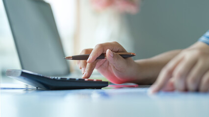 Closeup view of woman using calculator, counting money, expenses, analyzing bills, managing household finances.