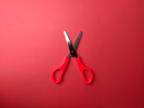Red scissors on a red background