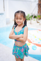 Smiling Girl wearing colorful swimsuit in pool.