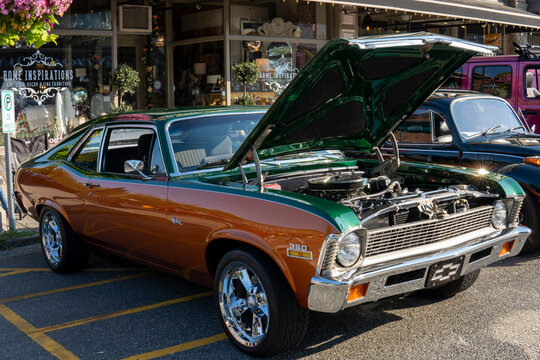 Snohomish, WA, USA - September 2022. Green and orange retro Chevrolet Nova with open car hood. 1972 Green and orange Chevy Nova at car exhibition