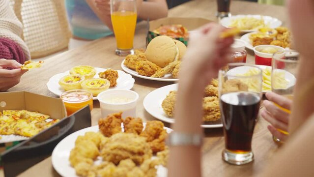 Group of Young Asian man and woman friends having dinner party eating food and drinking soft drink together at home. Happy people friends have fun reunion meeting celebration party on holiday vacation