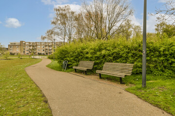 a park bench in the middle of an urban area with trees and bushes on either side of the path that leads to apartment buildings